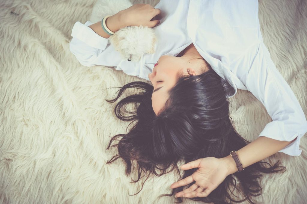woman lying on beige faux fur mat